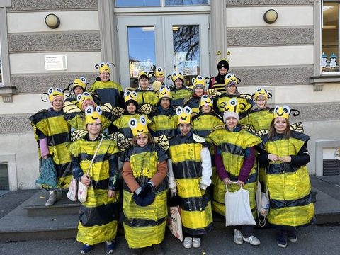 Kinder der Klassen 4a und 4b als Bienen verkleidet als Gruppe vor dem Schulgebäude