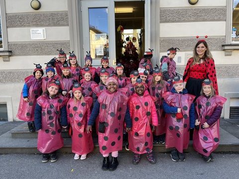 Kinder der Klassen 1a, 1b und 1c als Marienkäfer verkleidet als Gruppe vor dem Schulgebäude